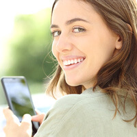 woman smiling while holding phone outside