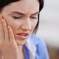 Close-up of woman rubbing jaw due to discomfort