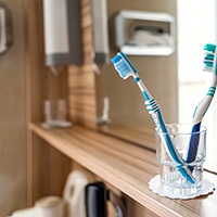 Two toothbrushes in an empty glass