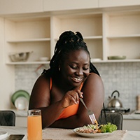 Woman smiling while eating salad in kitchen