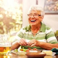 Senior woman sitting at table eating breakfast