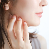 a woman touching her jaw due to tmj disorder