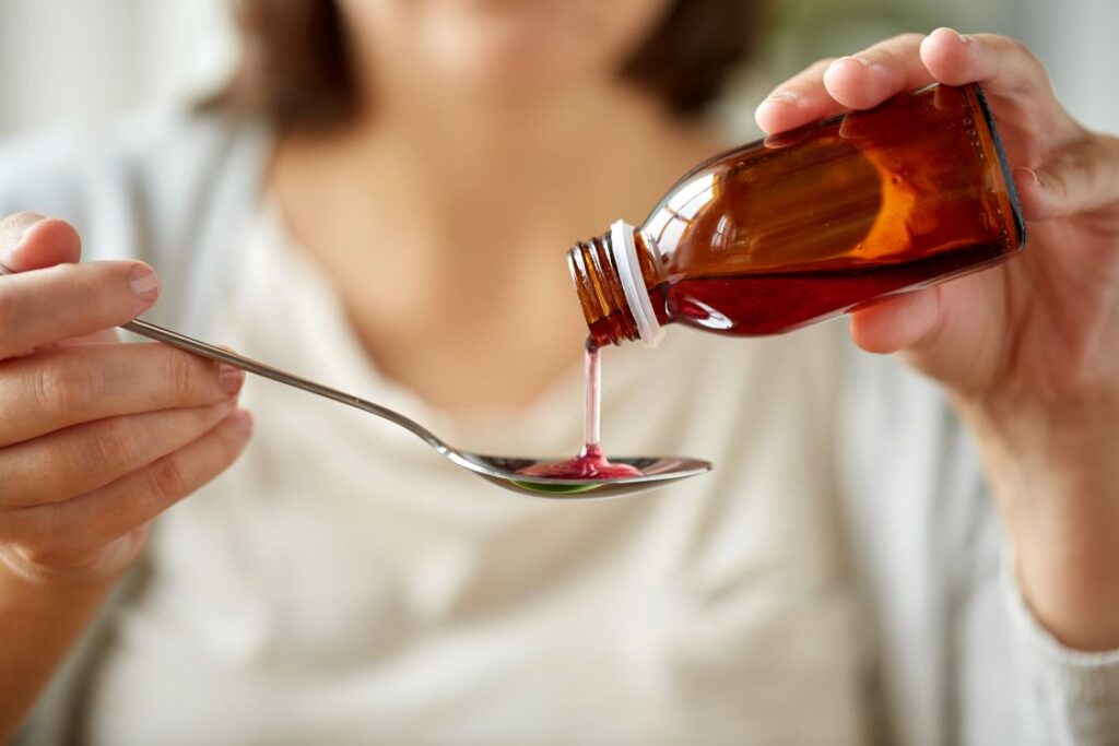 A woman pouring cough syrup.